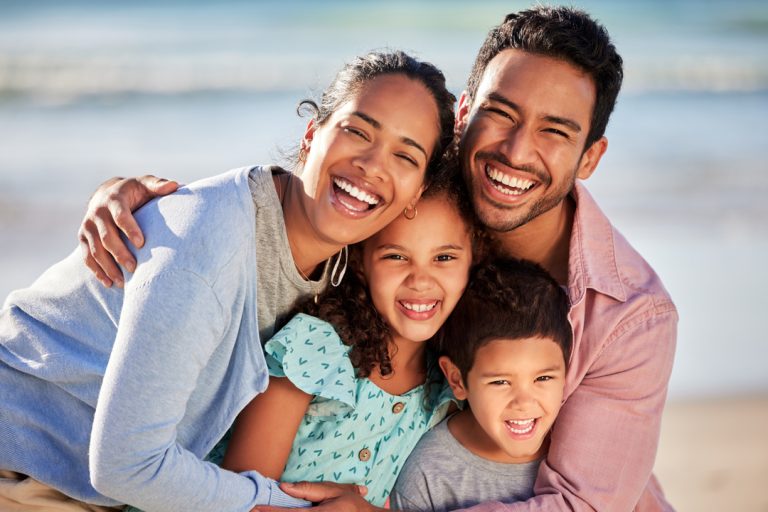 Smiling family of four hugging outdoors